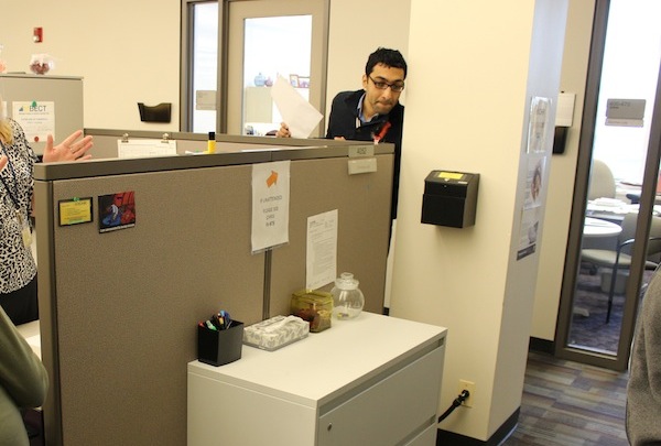 A staff member showing the team a drawer with poosters in it.