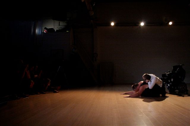 two dancers, one prone on floor, the other on top,  on wide dance floor