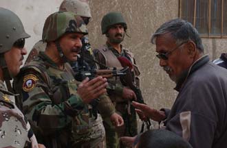 Iraqi National Police Col. Baha, brigade commander of the 5th Brigade, 2nd Division, Iraqi National Police (5/2 NP), addresses the concerns of a local gentleman while on a dismounted patrol in the Karkh District of Baghdad, Iraq, March 28. The police are conducting a presence patrol of the neighborhood to foster a closer relationship with the residents of the area. Photo by Staff Sgt. Sean Foley, Joint Combat Camera Center.